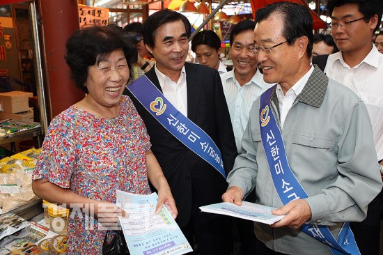 신한금융지주 라응찬 회장이 시장상인에게 안내장을 배포하며 미소금융을 소개하고 있다.