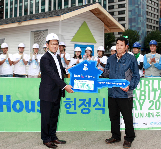 외환은행은 한국해비타트와 예스포인트 및 신용카드 기부 협약을 체결하고 4일 서울 시청광장에서 개최된 ‘2010 세계 주거의 날’ 행사에서 외환은행 정수천 부행장(왼쪽)이 홈파트너에게 무빙하우스 전달식을 갖고 기념촬영을 하고 있다.